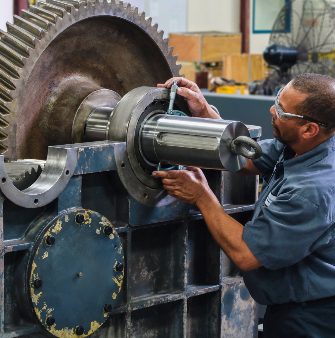 Technician inspecting a large industrial gearbox during repair service